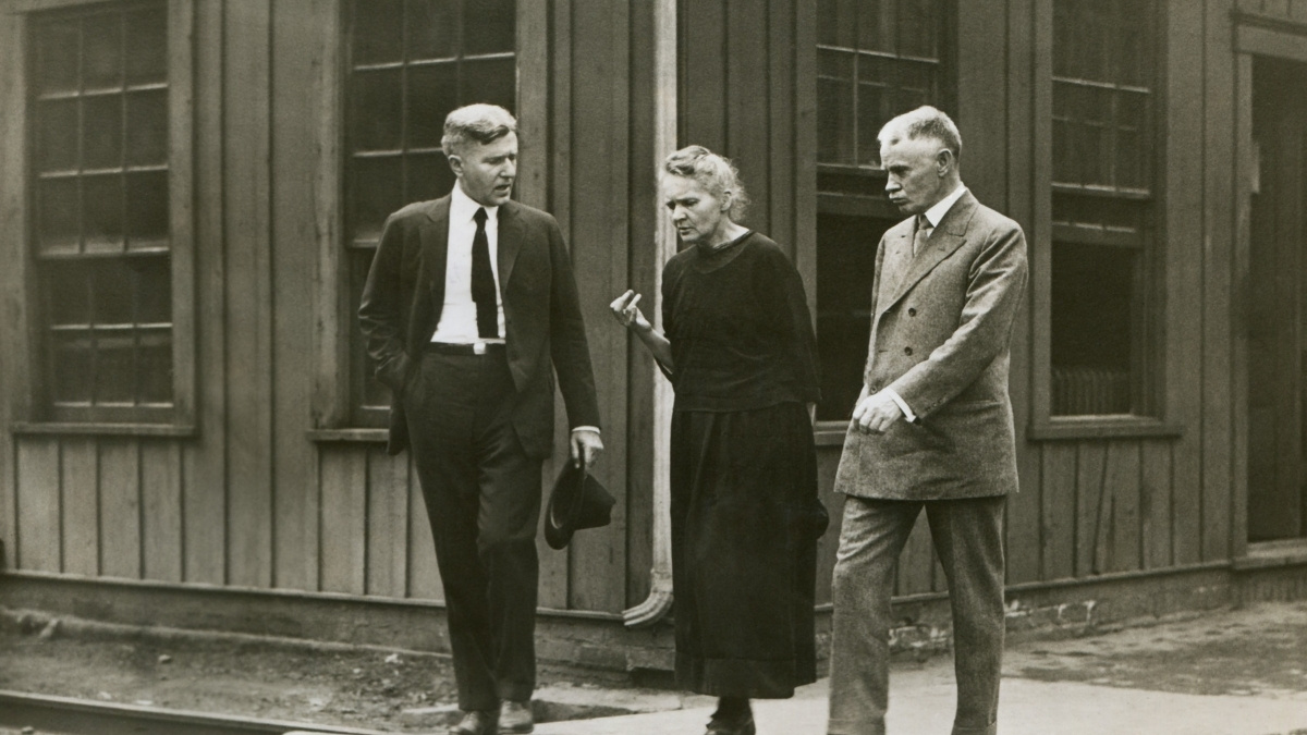 Marie Curie walking with fellow scientists at radium refinery plant in Pittsburgh