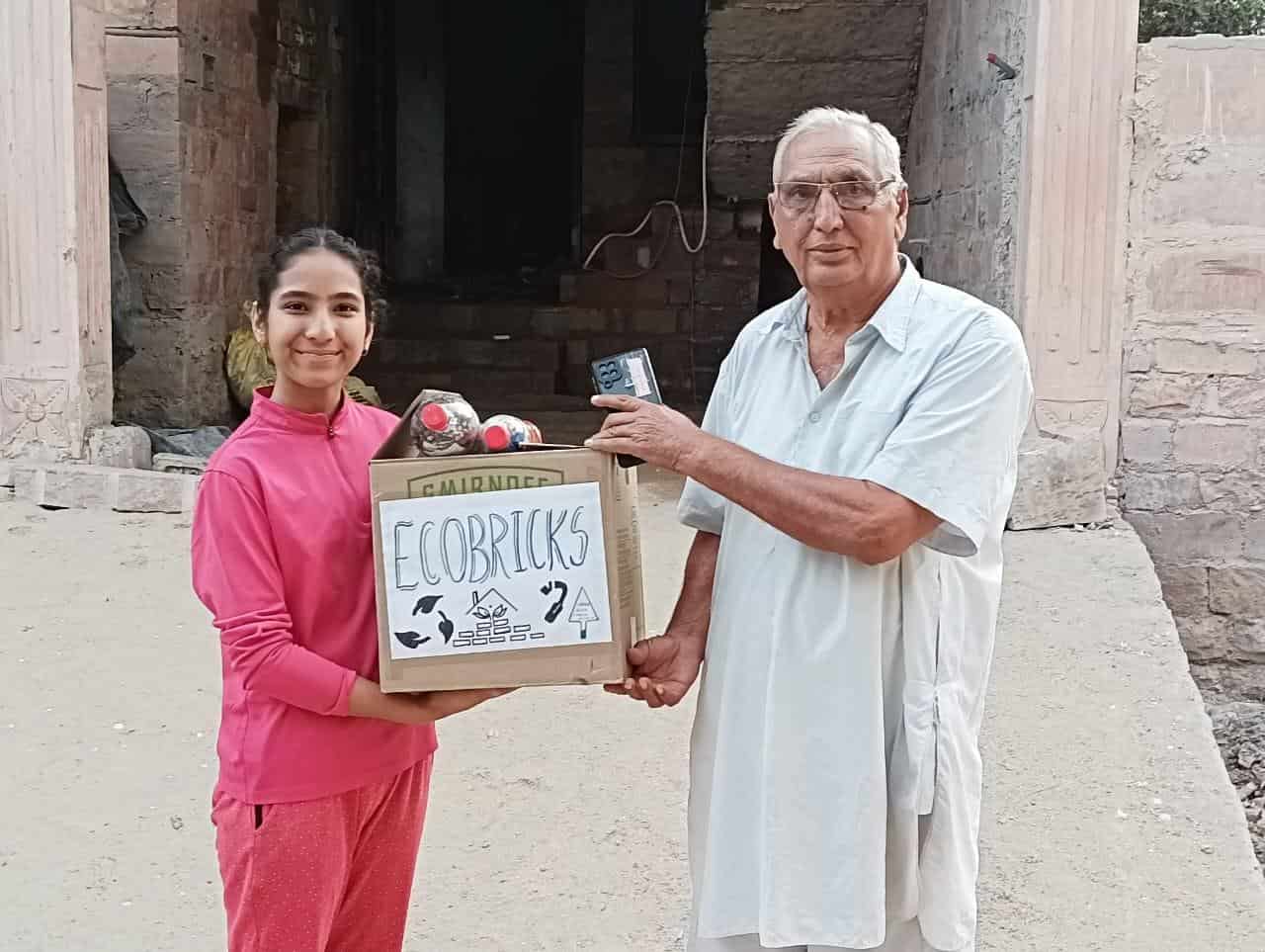 Apurva distributing eco-bricks for the construction of a house with a Senior Citizen.